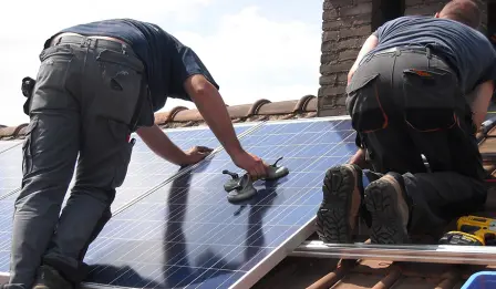 Deux techniciens installant des panneaux solaires sur un toit, assurant une pose professionnelle et sécurisée.