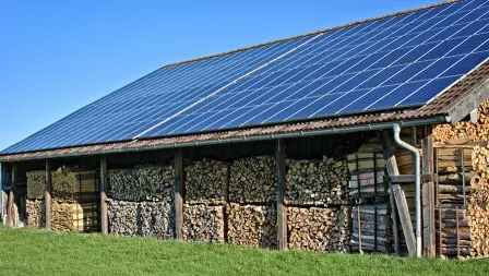 Panneaux solaires installés sur le toit d'une grange stockant du bois, optimisant la production d'énergie renouvelable.